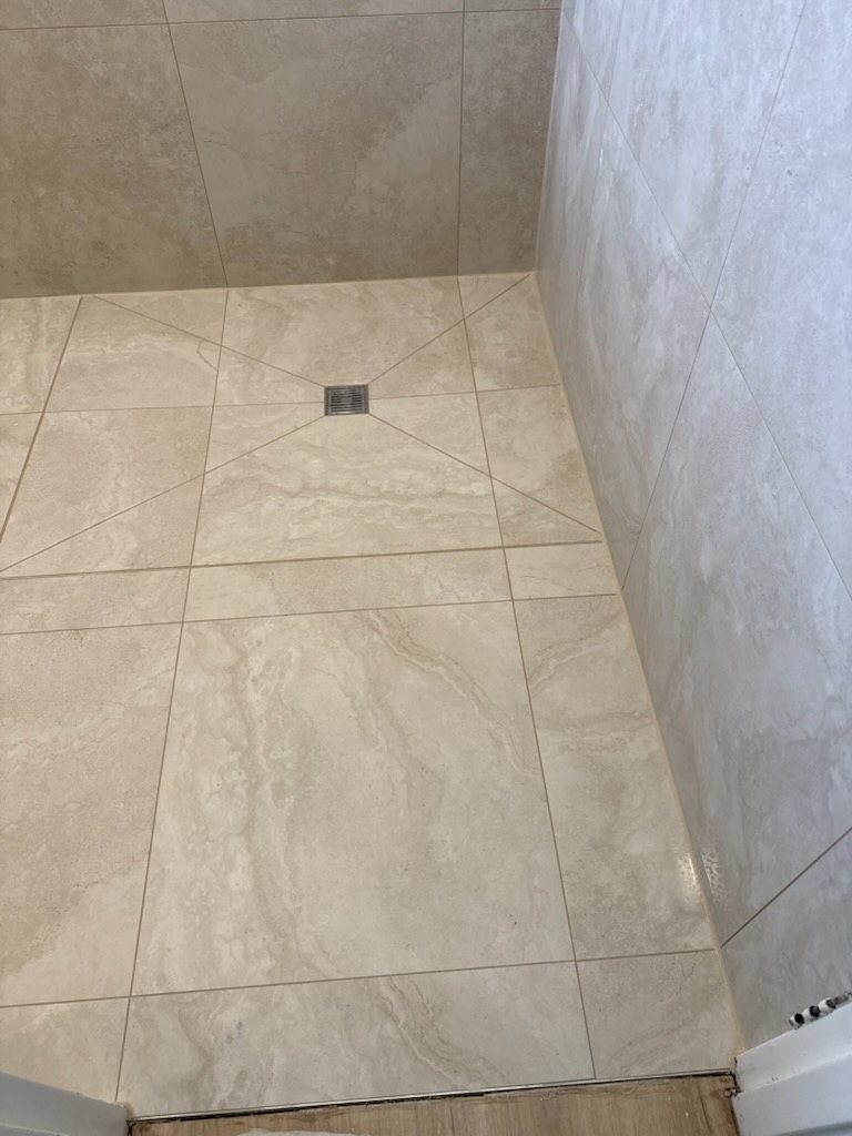 Tiled shower floor screeded and cut to fall evenly into a central drain