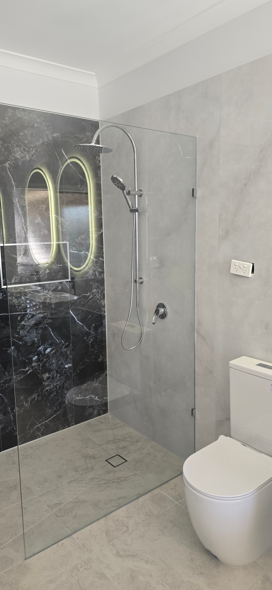 Walk-in shower with black marble feature wall and frameless glass screen